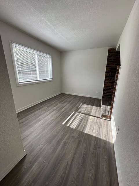 A room with wooden flooring and a window with blinds.