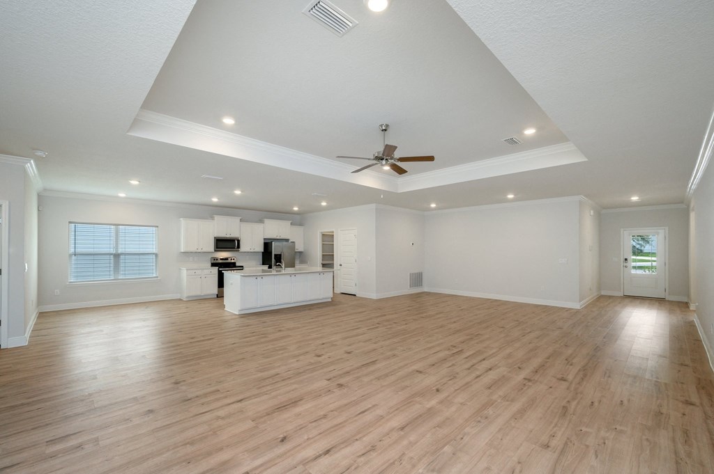 an open living room with a ceiling fan and a kitchen