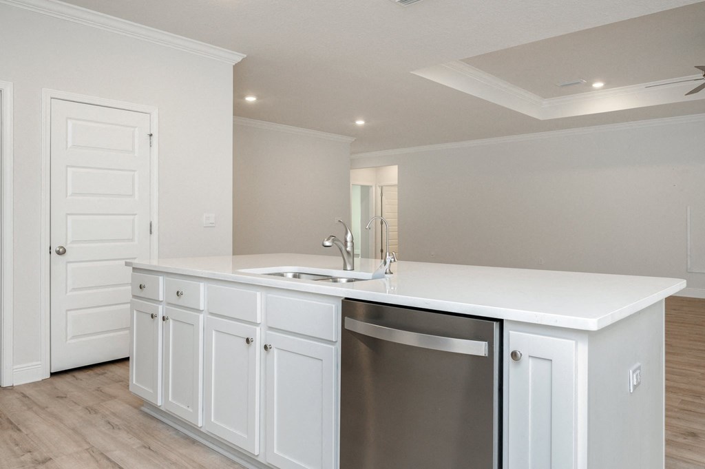 a kitchen with white cabinets and a stainless steel dishwasher