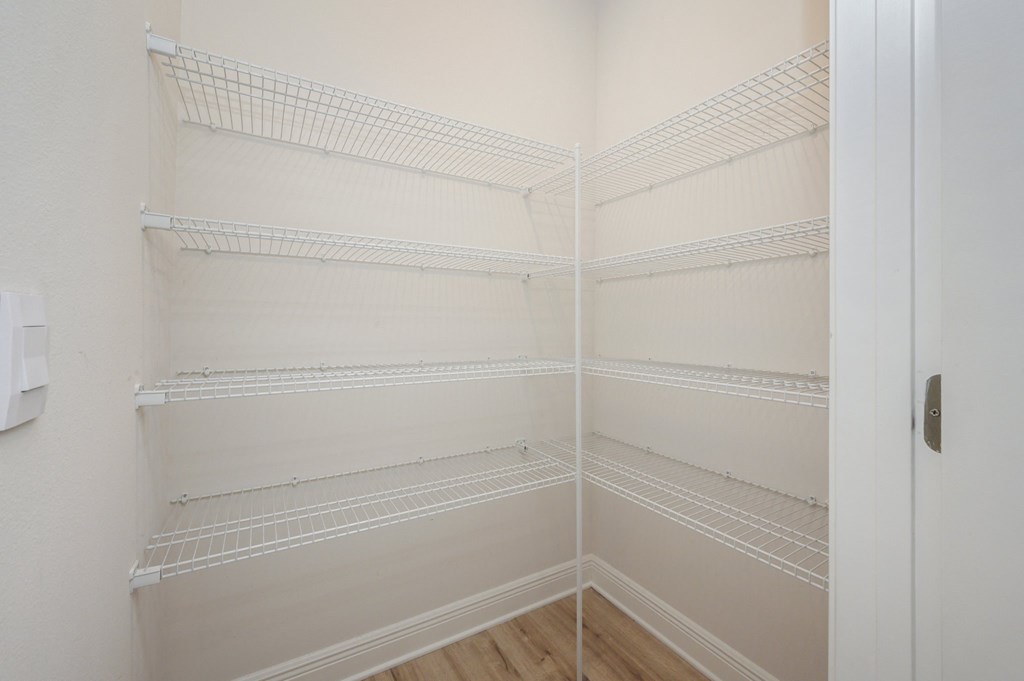 the walk in closet in a bedroom with white walls and shelves
