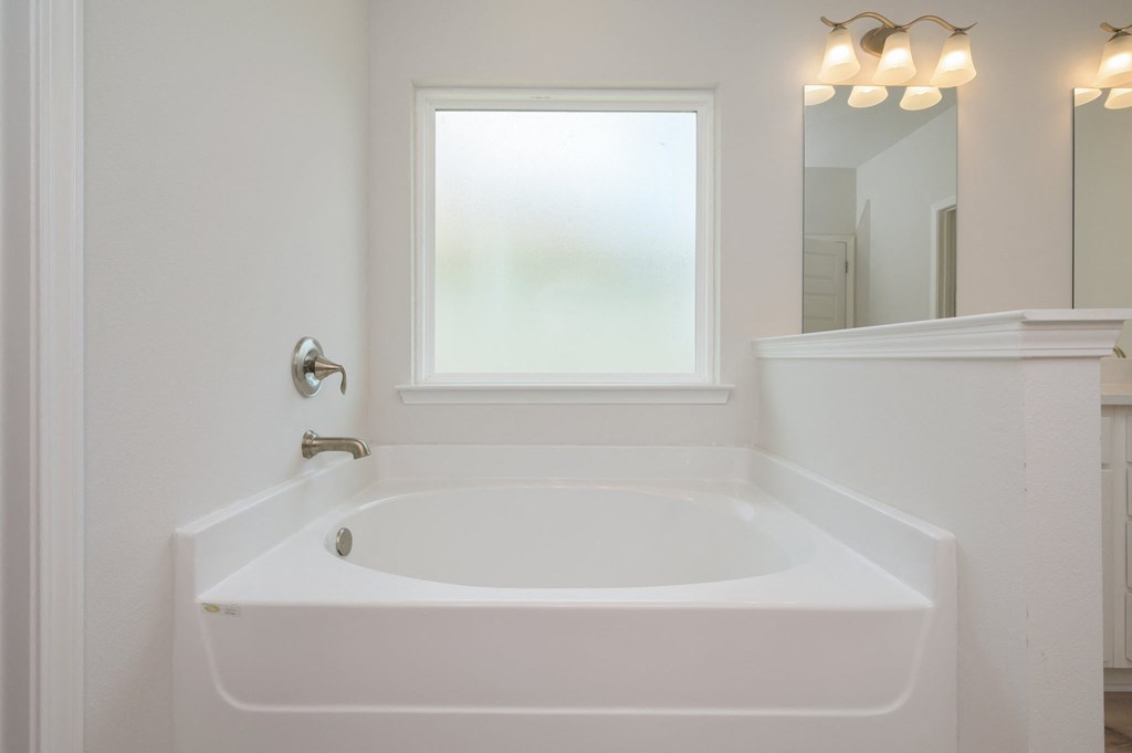 a white bathroom with a large tub and a window