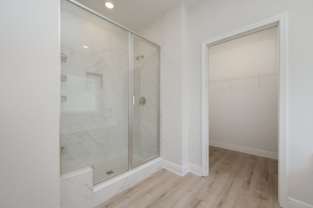 a renovated bathroom with a glass shower and wood flooring