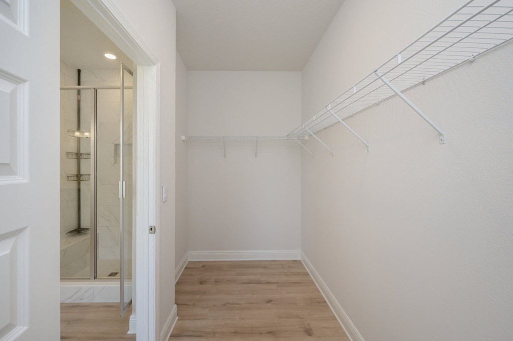 a bedroom with white walls and a closet with a mirrored closet door