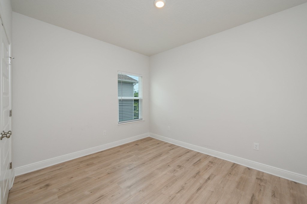 an empty bedroom with white walls and wood flooring