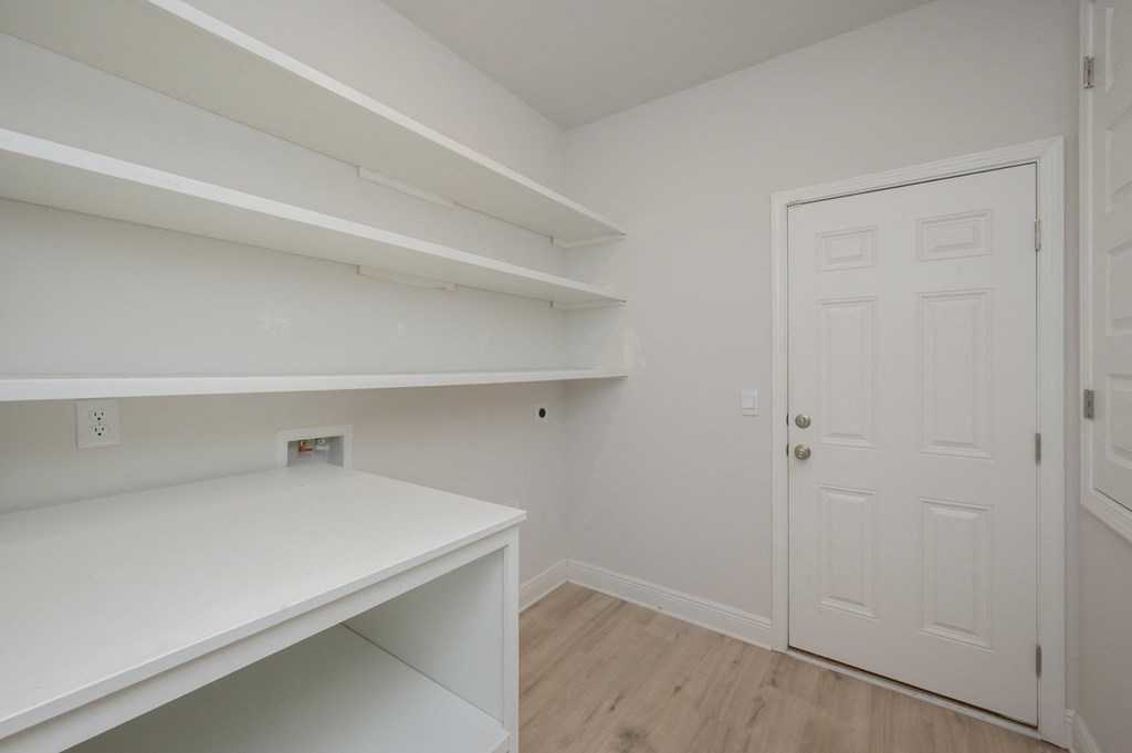 a room with white walls and a white desk and a door