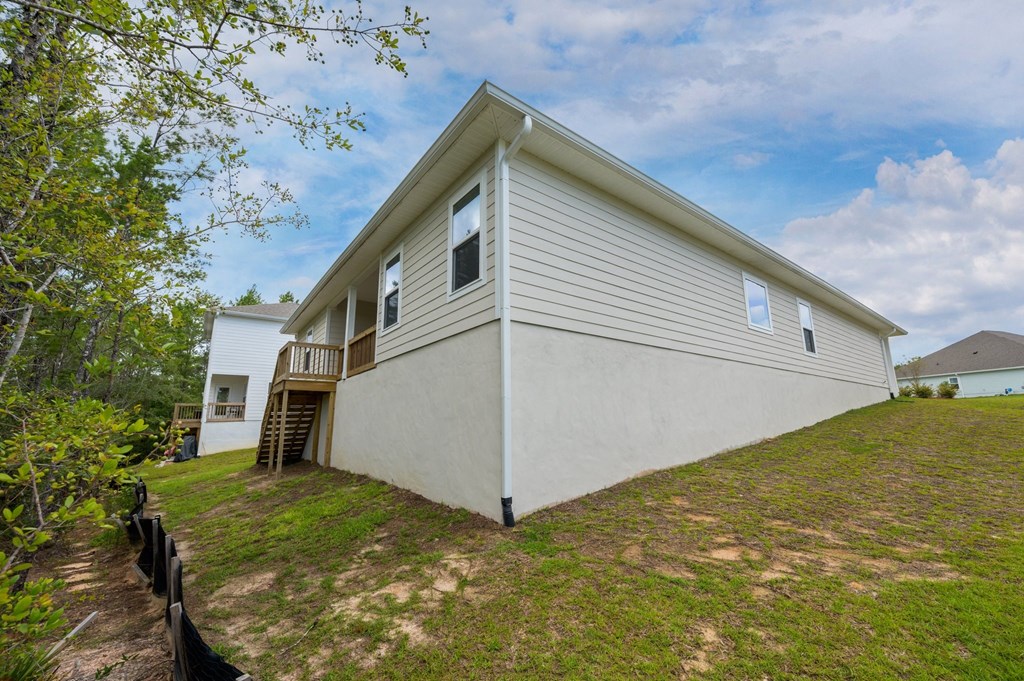 the back of a white house with a lawn and a tree