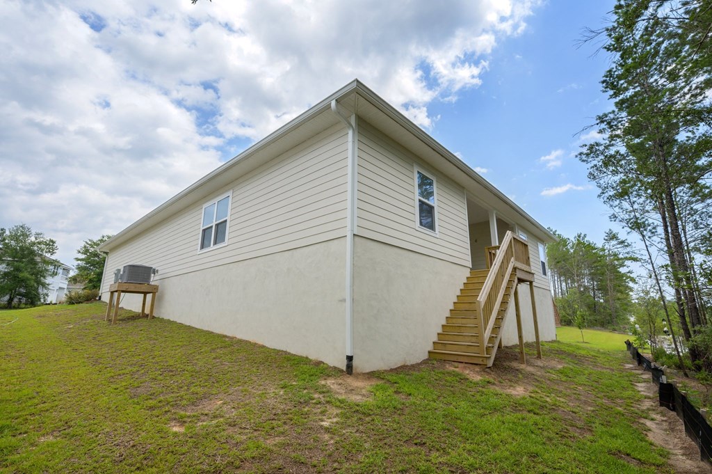 the back of a white house with stairs and a yard