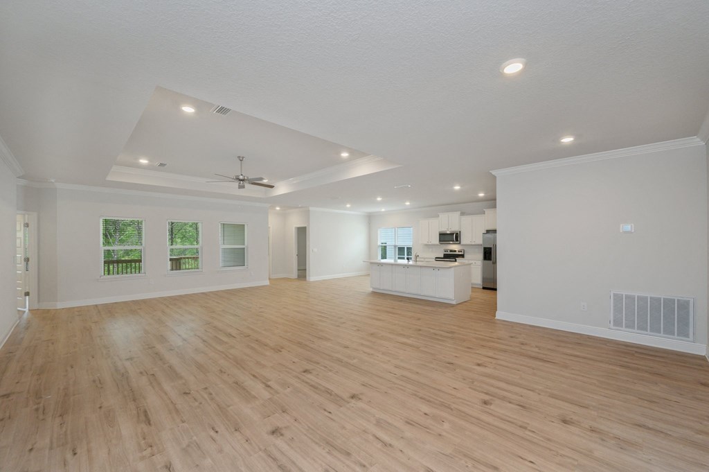 the living room and kitchen of a new home with white walls and wood flooring