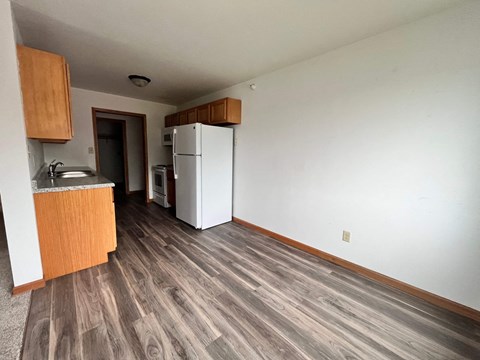 an empty room with a refrigerator and a kitchen