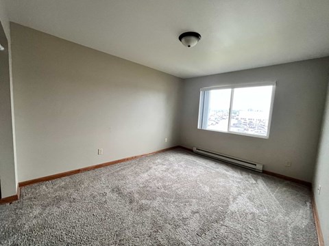 an empty room with a window and carpet
