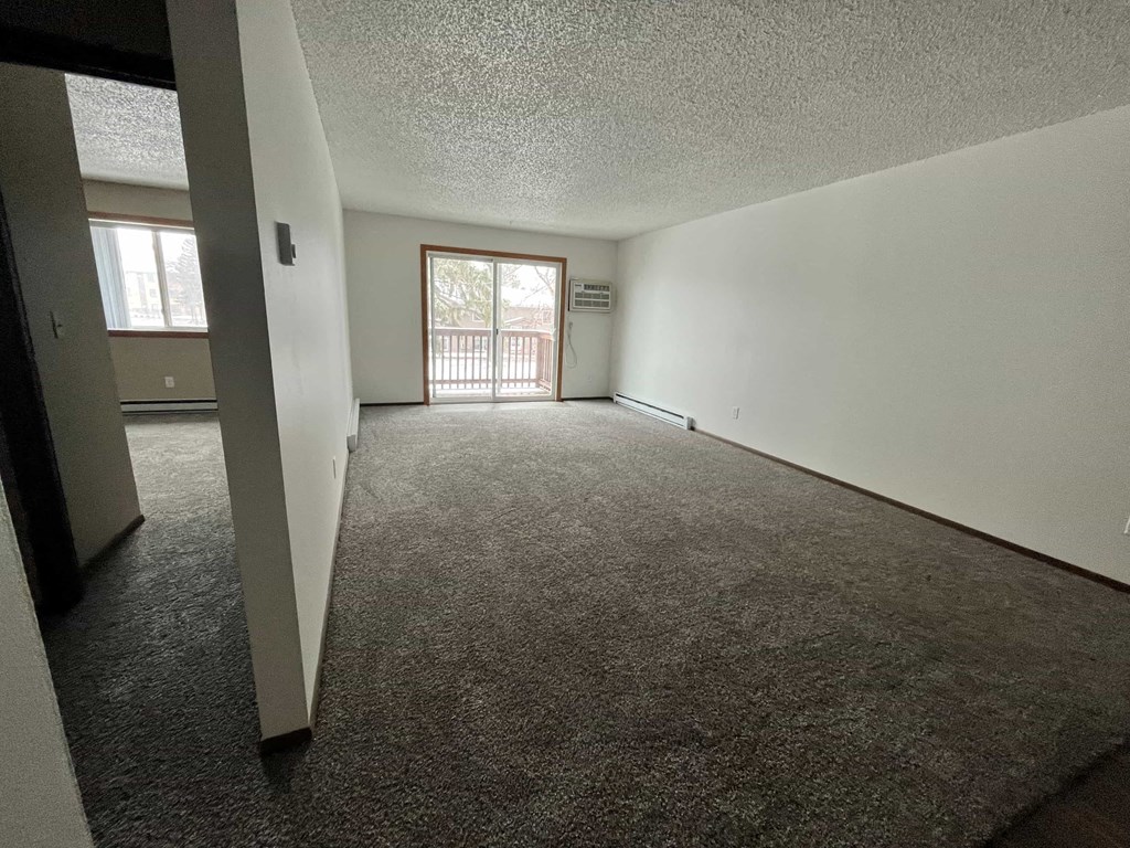 an empty living room with carpet and a sliding glass door
