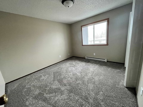 the living room of a house with carpet and a window