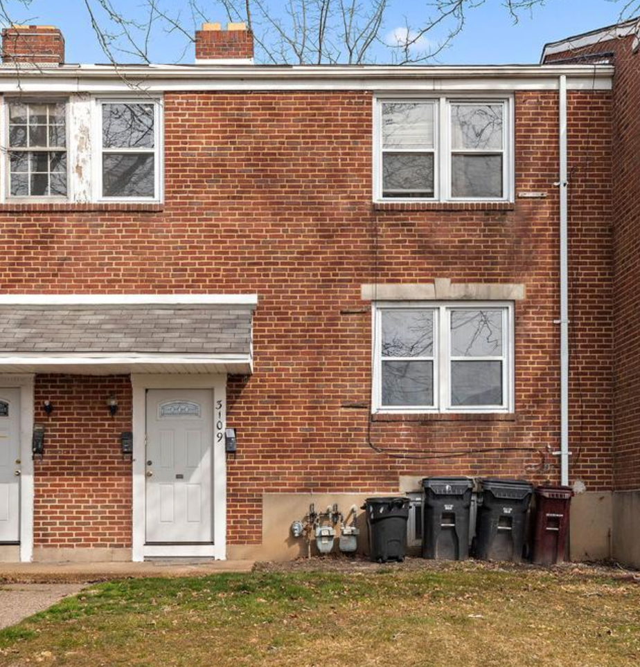 a brick house with trash cans in front of it
