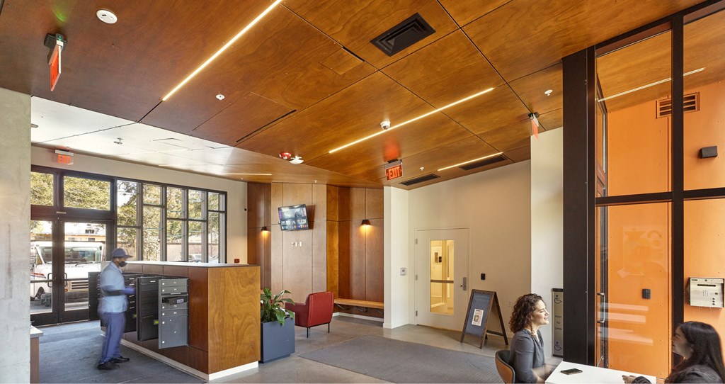 A man is standing in a room with a woman sitting at a desk.