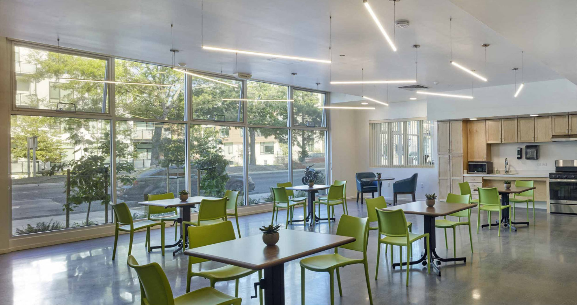 A room with tables and chairs and a kitchen area.