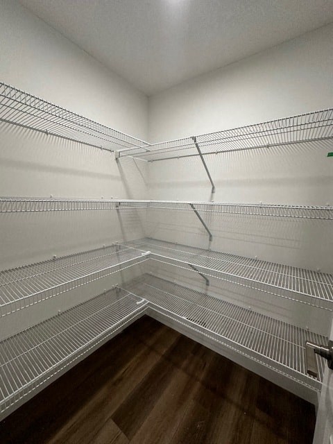 a walk in closet with empty shelves and a wood floor