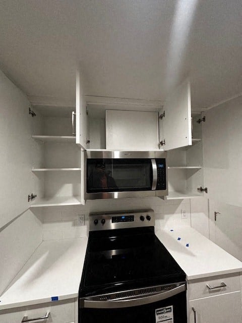 a white kitchen with a stove and a microwave