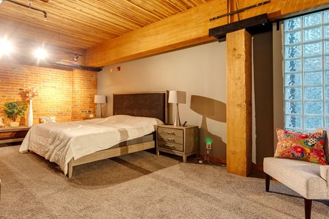 A bedroom with a bed, nightstand, and chair.