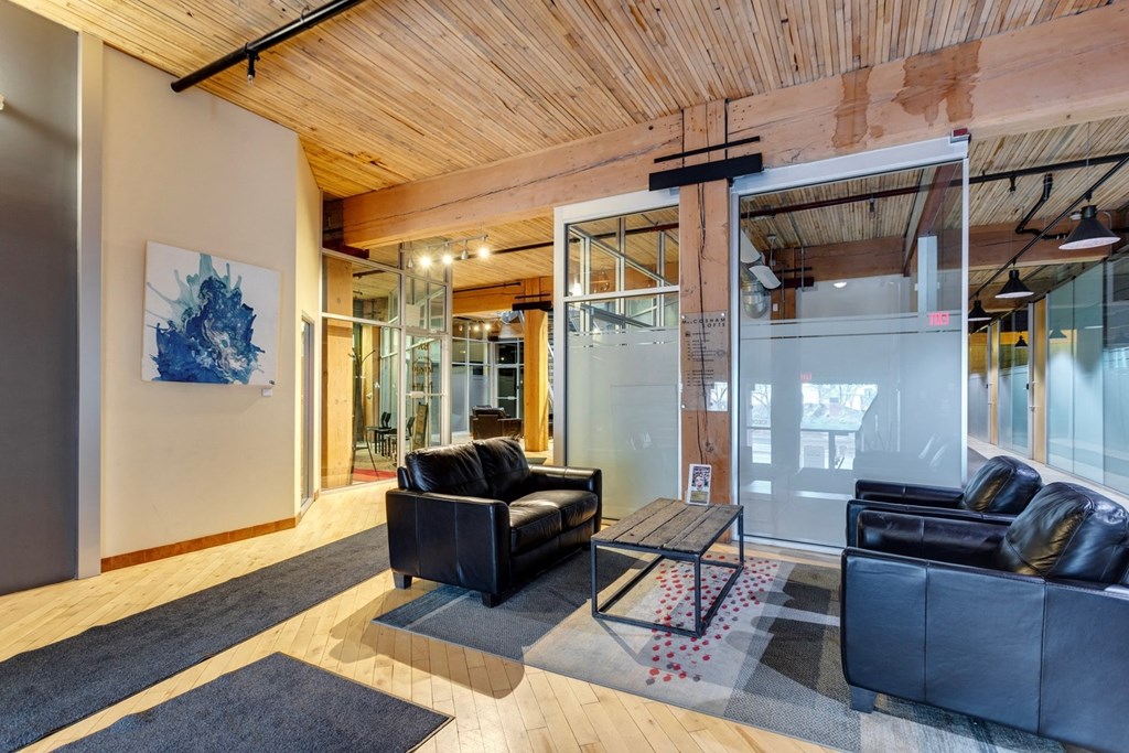 A modern living room with a black couch and a wooden ceiling.