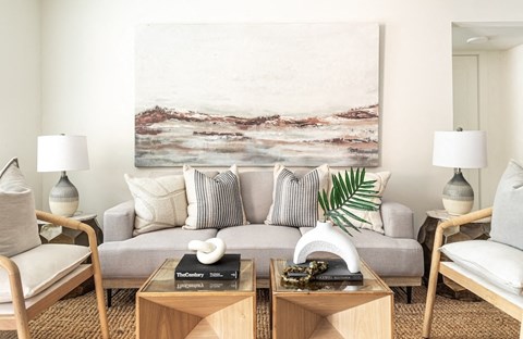 a living room with a gray couch and a painting on the wall