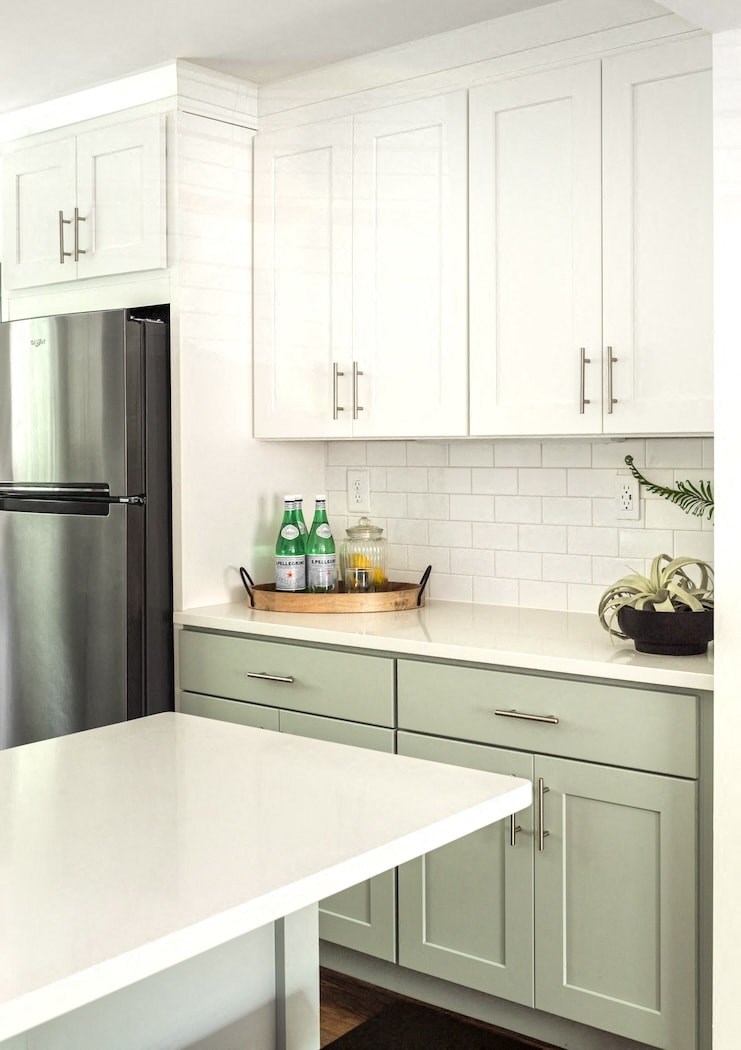 a white kitchen with gray cabinets and a stainless steel refrigerator