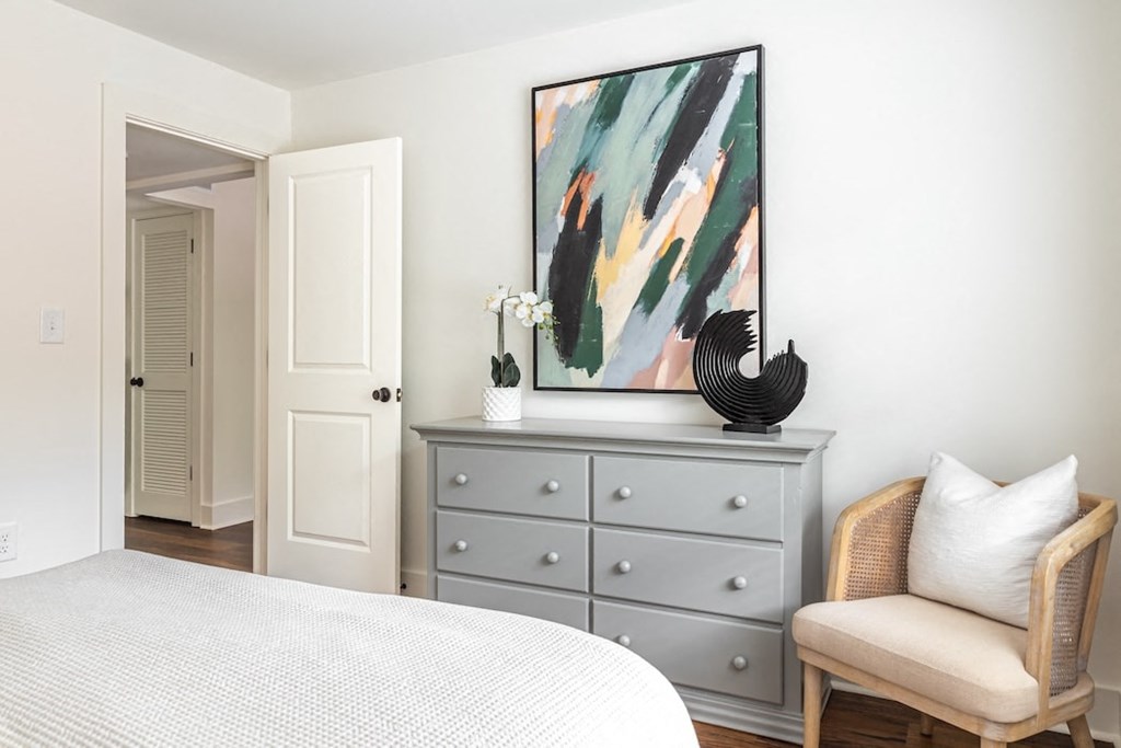 a bedroom with a bed and a dresser with a painting on it