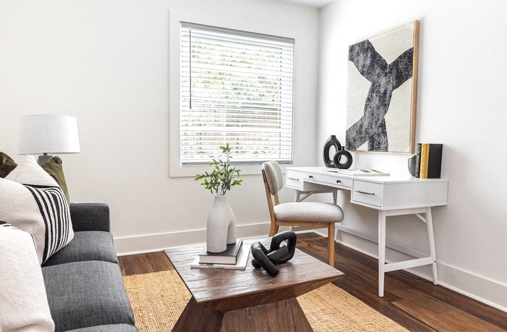 a living room with a couch and a desk and a window