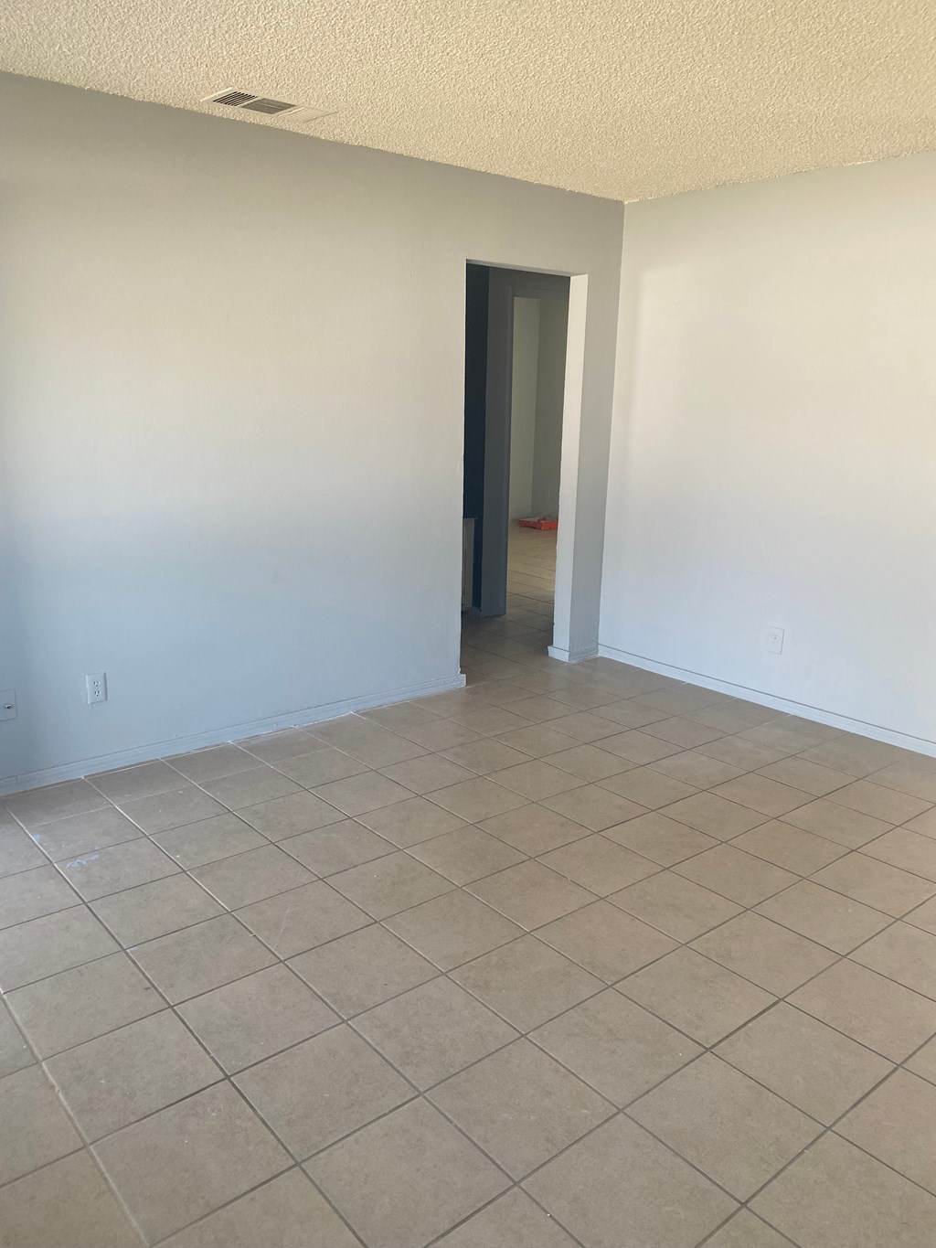 an empty living room with a tile floor and white walls