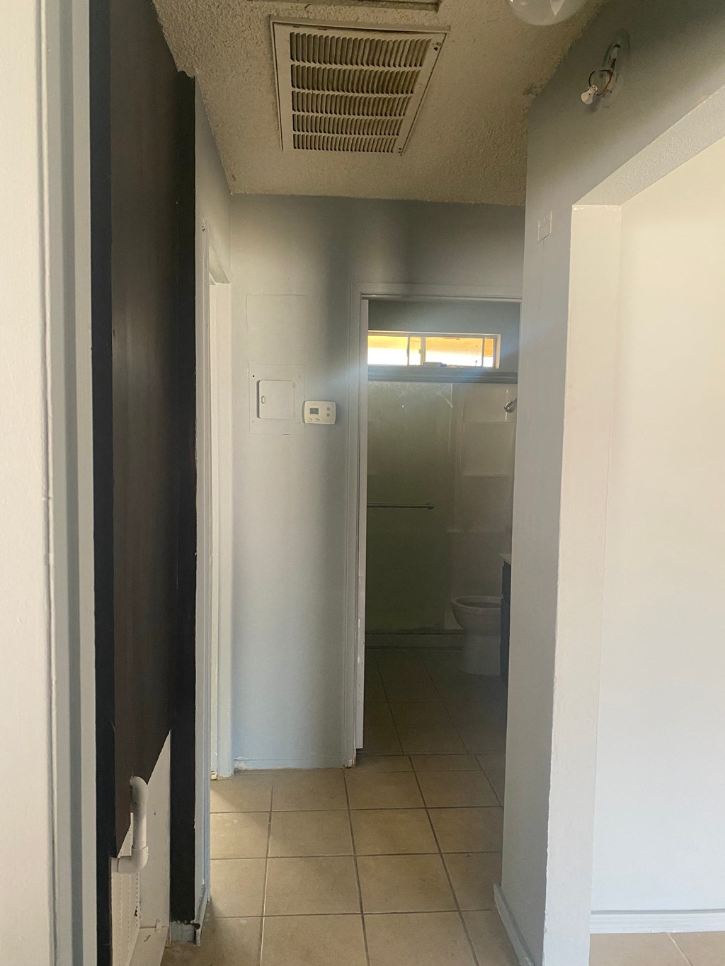 a hallway with a door to a bathroom and a toilet