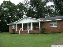 a red brick house with a porch and a green lawn