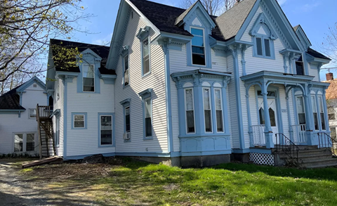 A large white house with blue trim and a black roof.