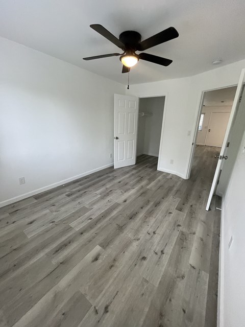 A room with a ceiling fan and wooden flooring.
