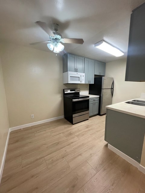 A kitchen with a fan on the ceiling and a refrigerator.