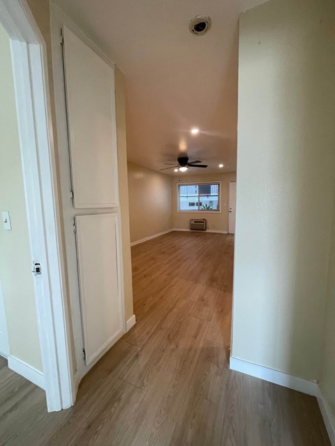 A long hallway with a door on the left and a window on the right.