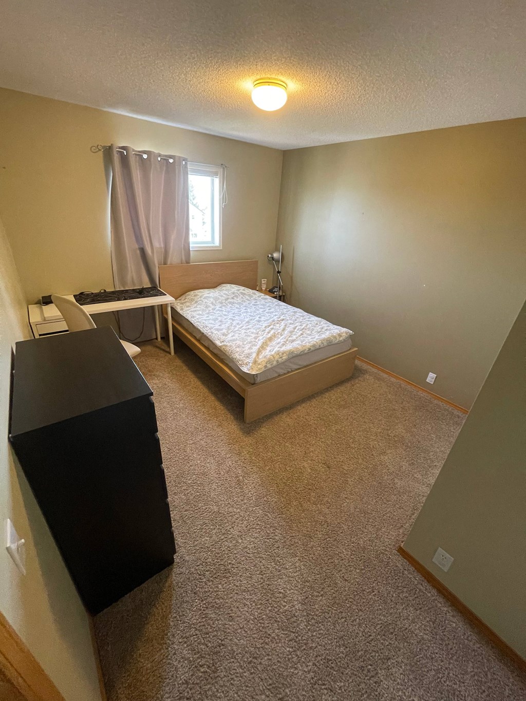 a bedroom with a bed and a dresser and a window