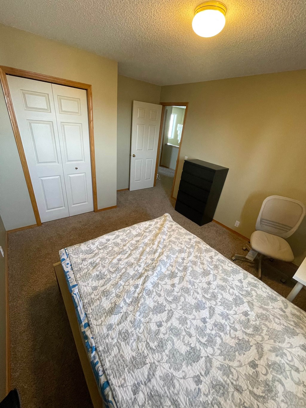 an empty bedroom with a bed and a dresser and a closet