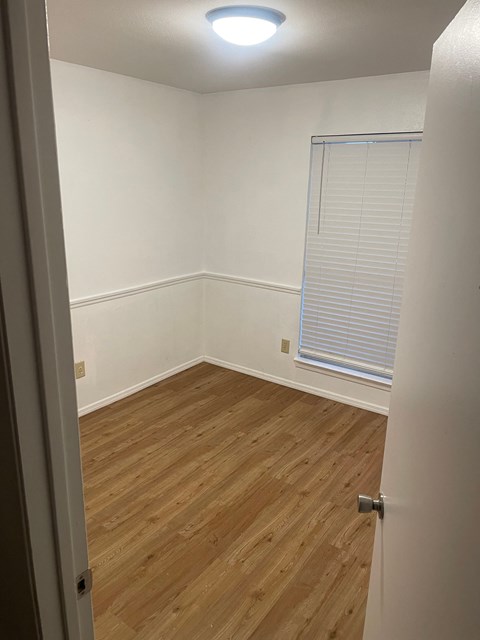 a bedroom with wood flooring and a window