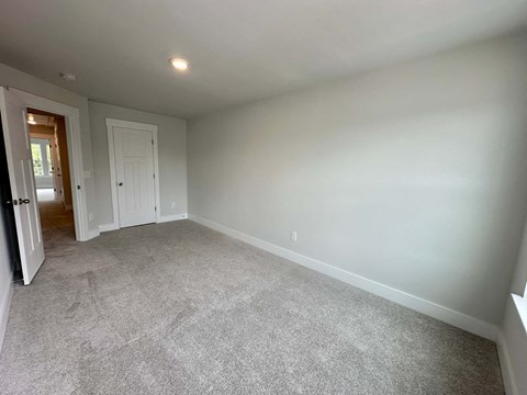 a living room with carpet and a door into a bedroom