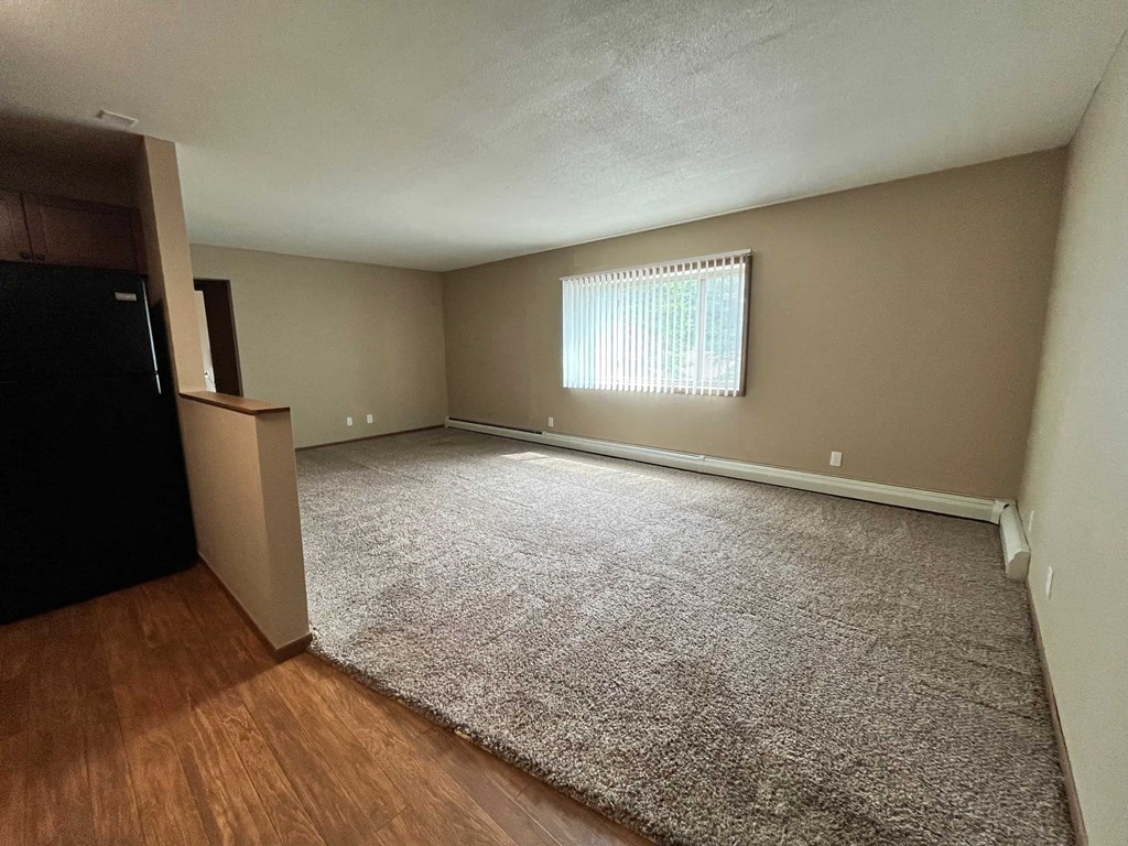 an empty living room with wood floors and a window