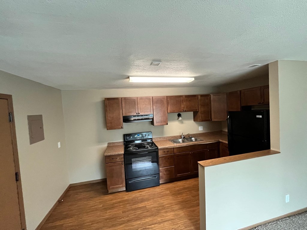 an empty kitchen with wooden cabinets and black appliances