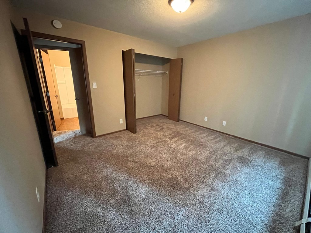 a empty living room with carpet and a door to a closet