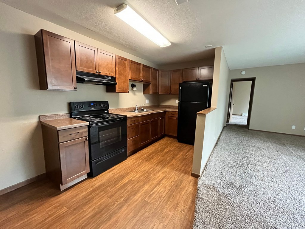 an empty kitchen with black appliances and wood flooring