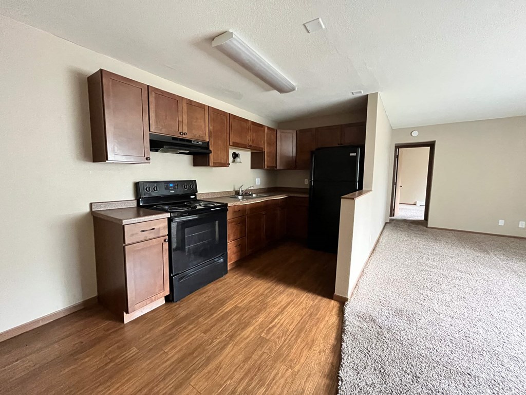 an empty kitchen with black appliances and wooden cabinets