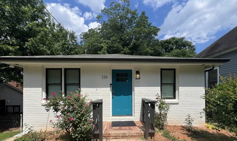 the front of a white house with a blue door