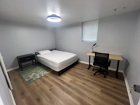A bedroom with a bed, desk, and chair.