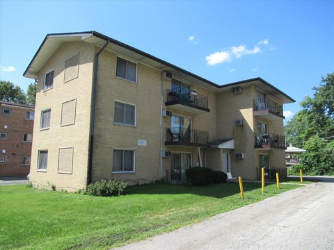 A tan apartment building with a balcony on the second floor.