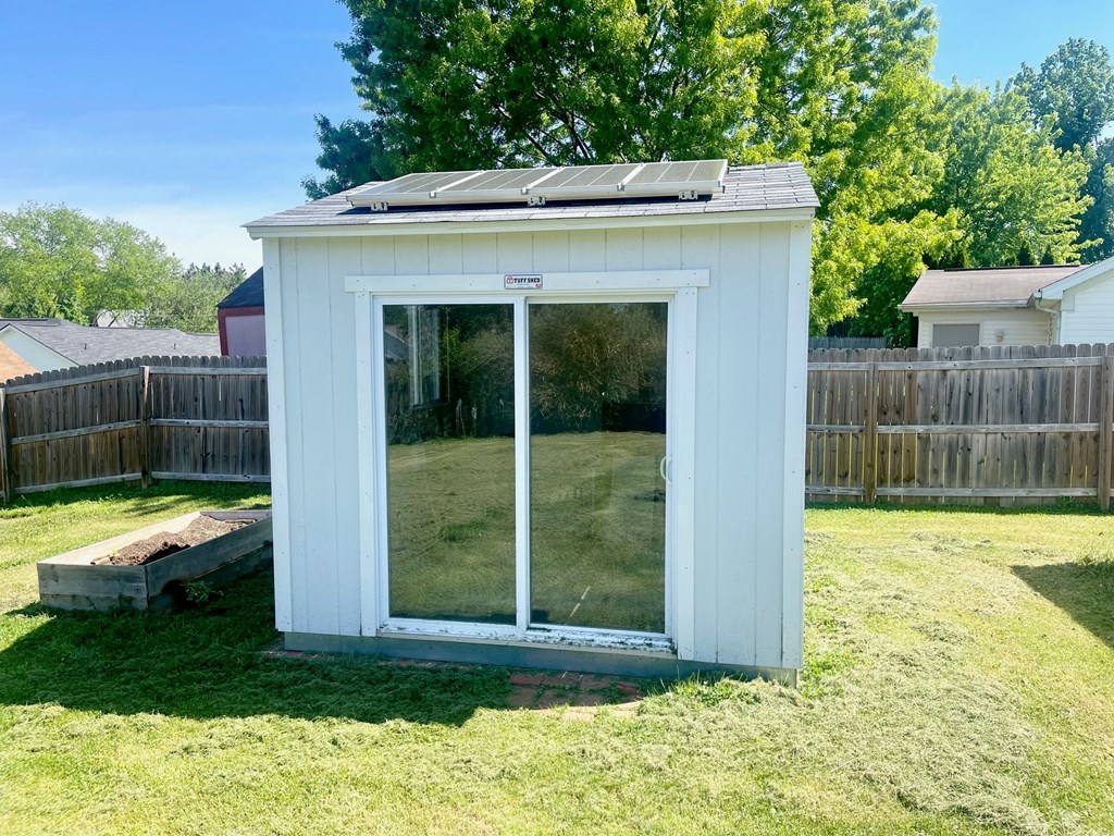 a small white shed in the backyard with a glass door