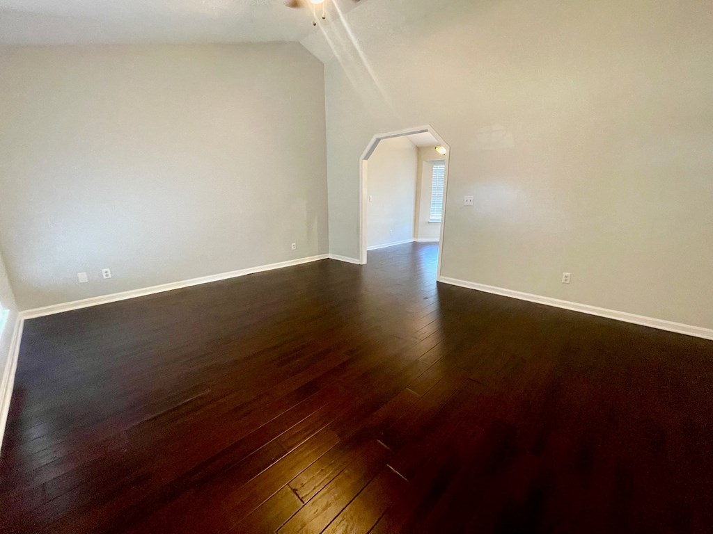 an empty living room with hardwood flooring and white walls