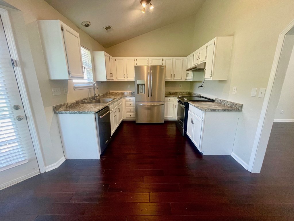an empty kitchen with white cabinets and stainless steel appliances