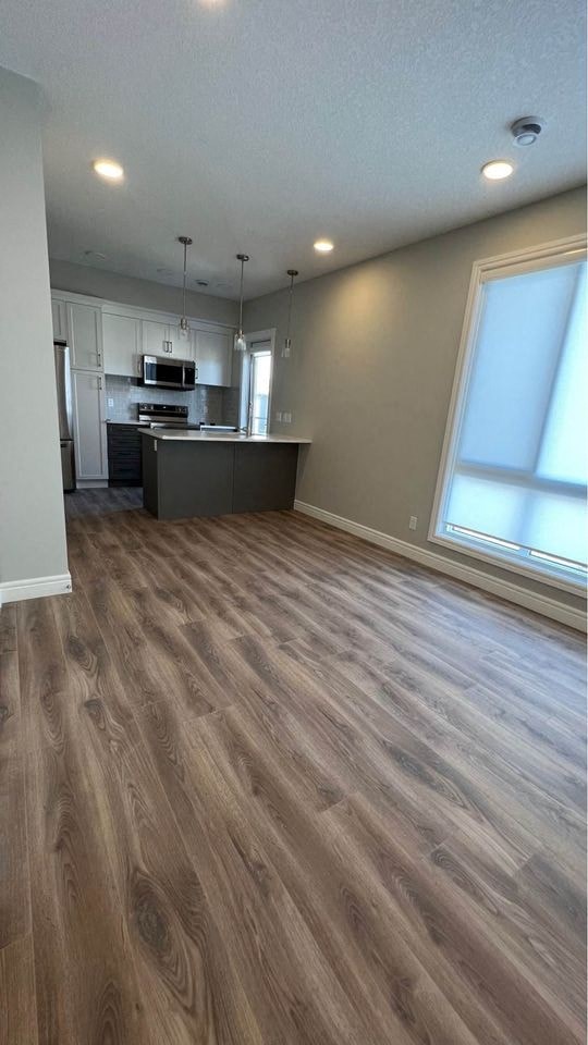 an empty kitchen and living room with a wooden floor